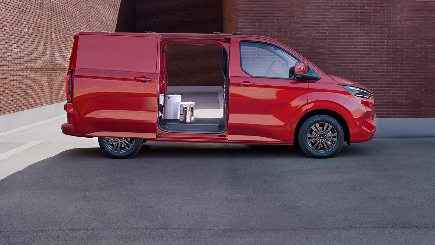 Punainen Ford Transit Custom -pakettiauto, jonka avoimista ovista näkyy sisätiloihin.