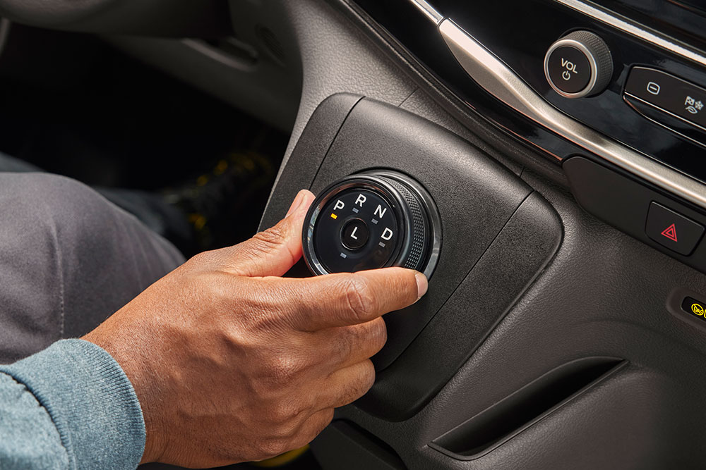 Lähikuva kädestä, joka kääntää vaihteenvalitsimen nuppia Ford E-Transit -sähköpakettiautossa.