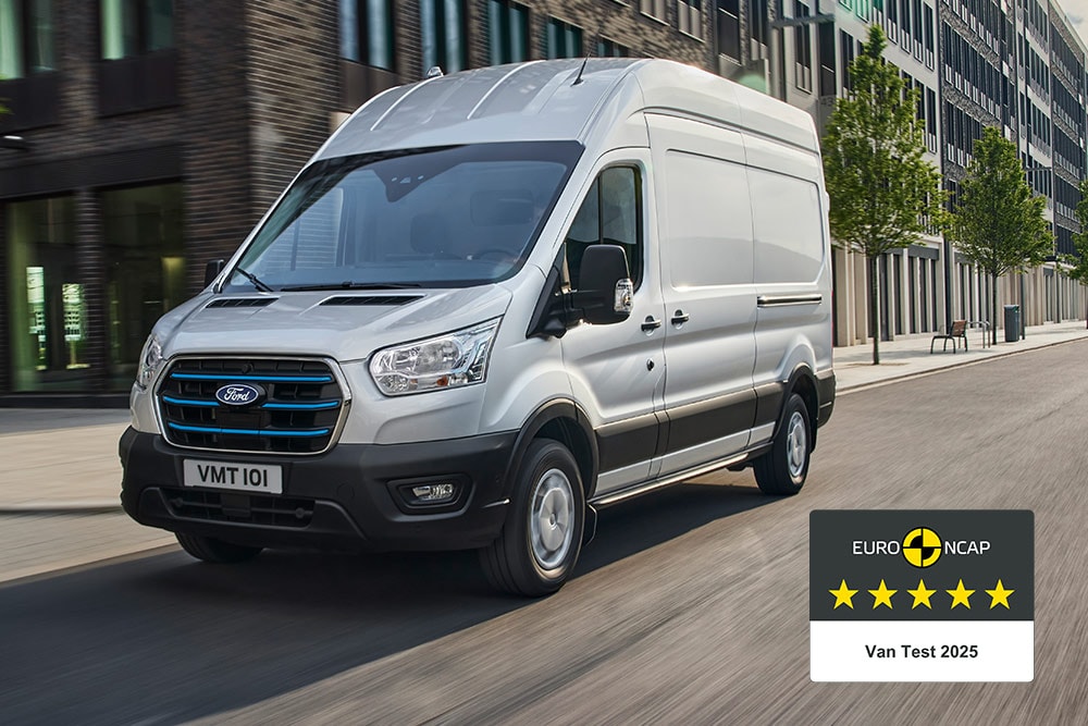 Hopeanvärinen Ford E-Transit -sähköpakettiauto ajamassa tiellä ja Gold 2022 Commercial Van Safety -merkki.