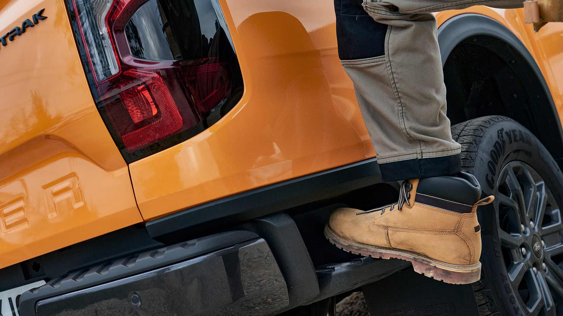 Työntekijä astumassa Ford Rangerin integroidulle takapuskurin askelmalle.