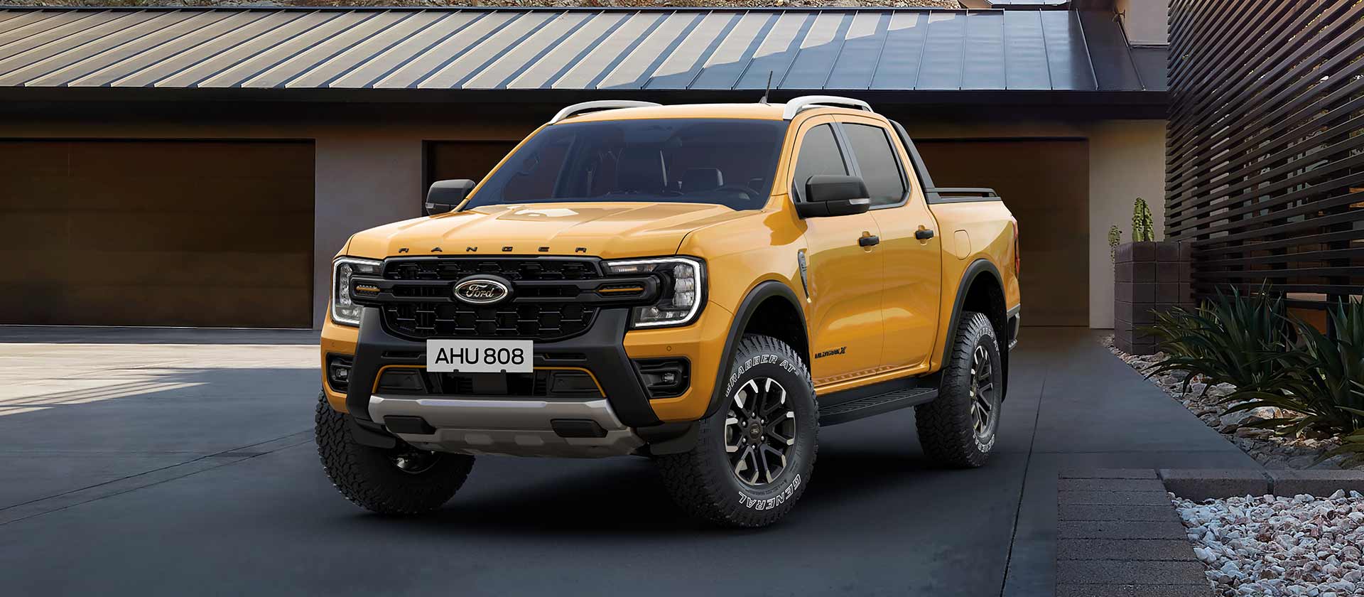 Keltainen 5-paikkainen Ford Ranger Double Cab pysäköitynä talon eteen.