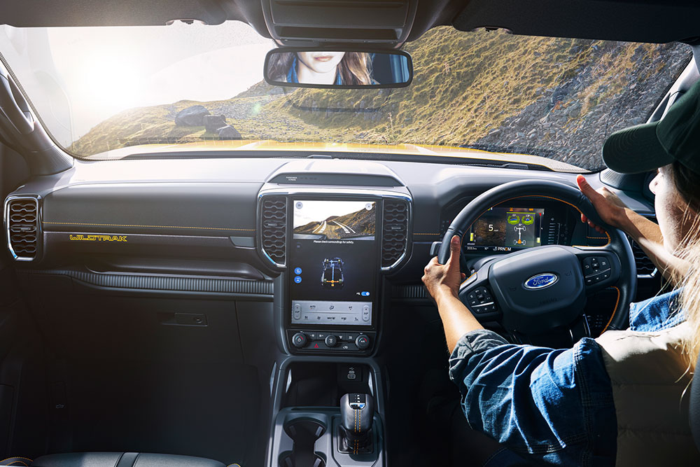 Kuljettaja pitää kiinni Ford Rangerin ohjauspyörästä ajaessaan mutkittelevalla vuoristotiellä.