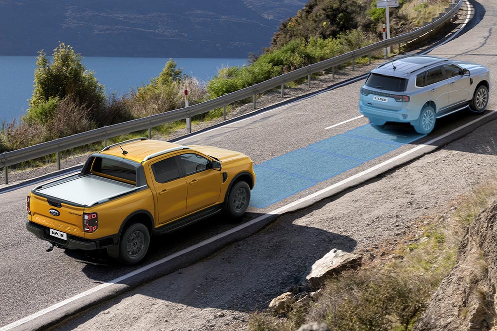 Keltainen Ford Ranger käyttää edistynyttä kuljettajaa avustavaa järjestelmää ajettaessa rannikkotiellä. 