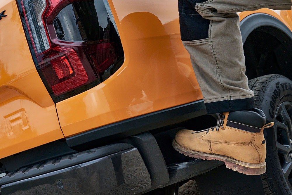 Työntekijä astumassa Ford Ranger Wildtrakin integroidulle taka-askelmalle.