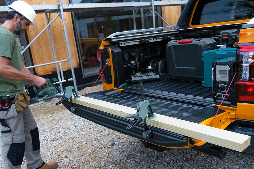 Henkilö työskentelemässä keltaisen Ford Ranger Double Cabin avoimen takalaidan ääressä.