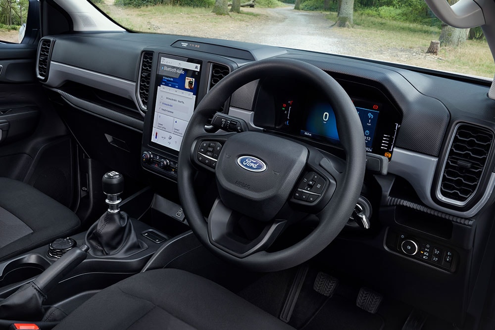 Ford Rangerin ohjaamosta sisätilakuva, jossa näkyvät ohjauspyörä ja manuaalivaihteiston vaihteenvalitsin.