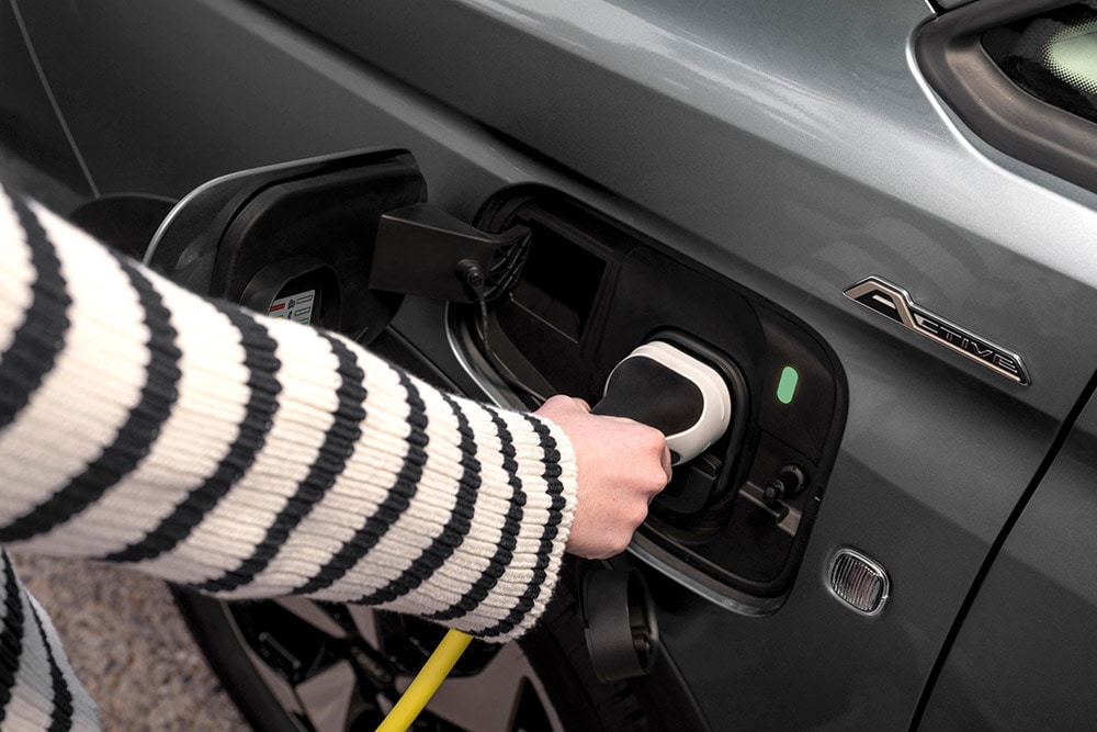 Henkilö liittämässä latauskaapelia ladattavaan Ford Transit Connect -hybridiin.