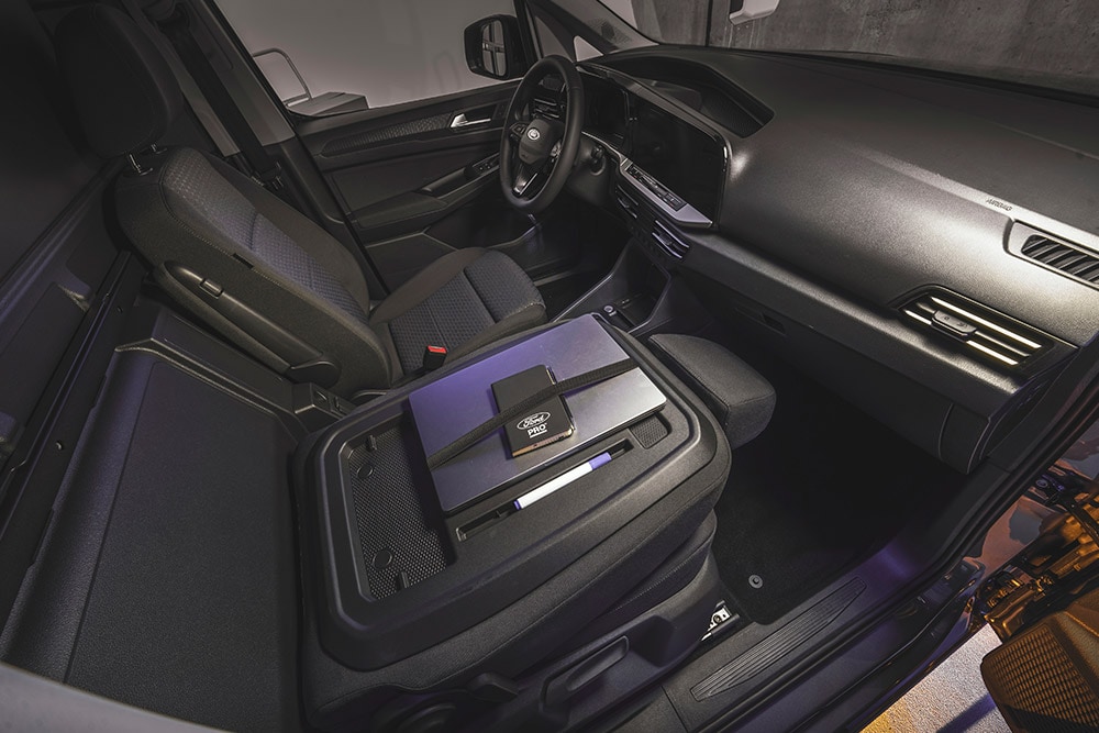  Ford Transit Connectin sisätilat, joissa näkyy kojelauta ja istuimet sekä kannettava tietokone ja puhelin keskikonsolissa.