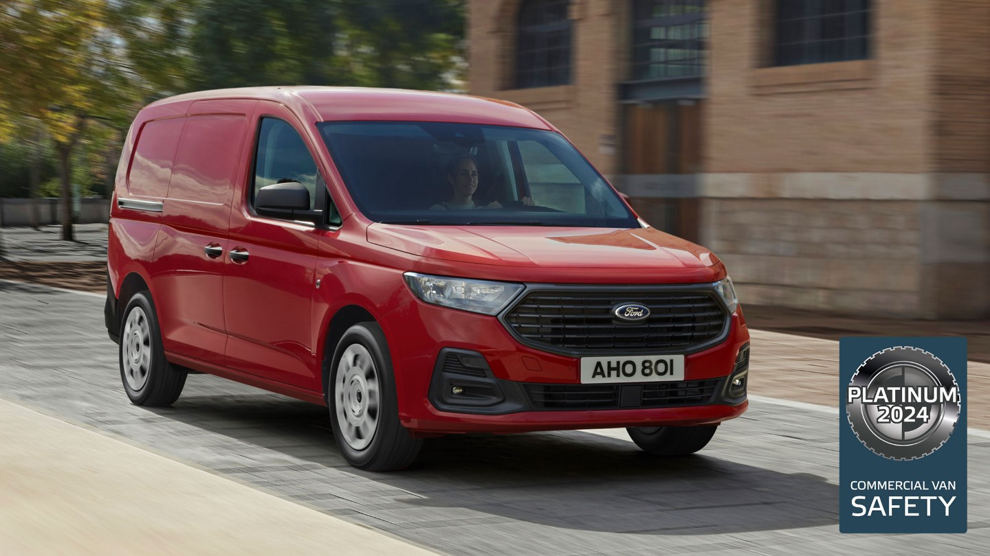 Täysin uusi Maple Red -värinen Ford Transit Connect Trend ajaa kadulla esitellen etusäleikköä ja automaattisia ajovaloja. 