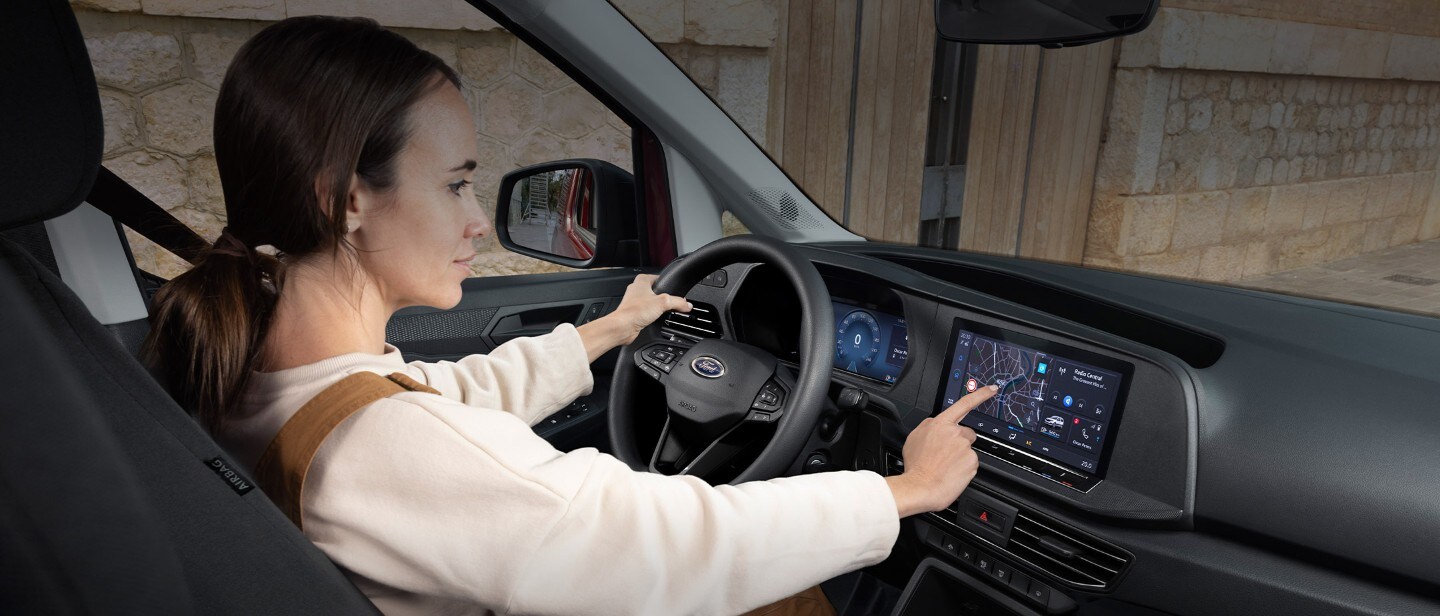 Nainen koskettaa 10" kosketusnäyttöä istuessaan täysin uuden Ford Transit Connectin kuljettajan istuimella.