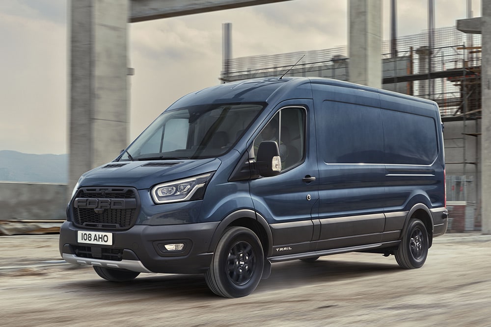 Valinnaisella Trail Packilla varustettu Ford Transit Van ajamassa teollisuusalueella. 