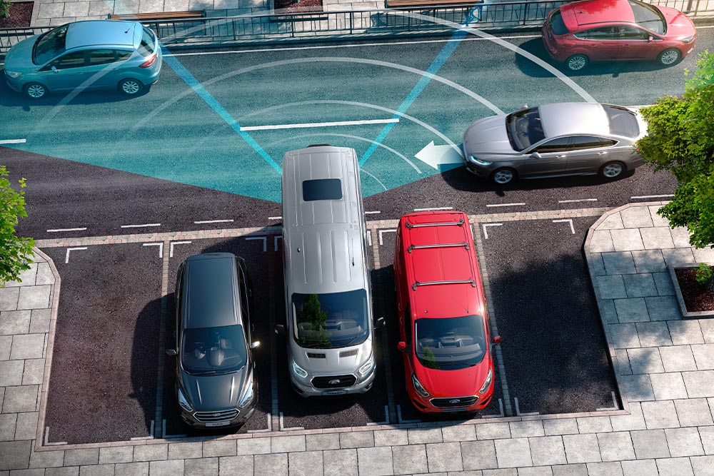 Hopeanvärinen Ford Transit Van peruuttamassa; siniset viivat kuvaavat takapysäköintianturien käyttöä. 