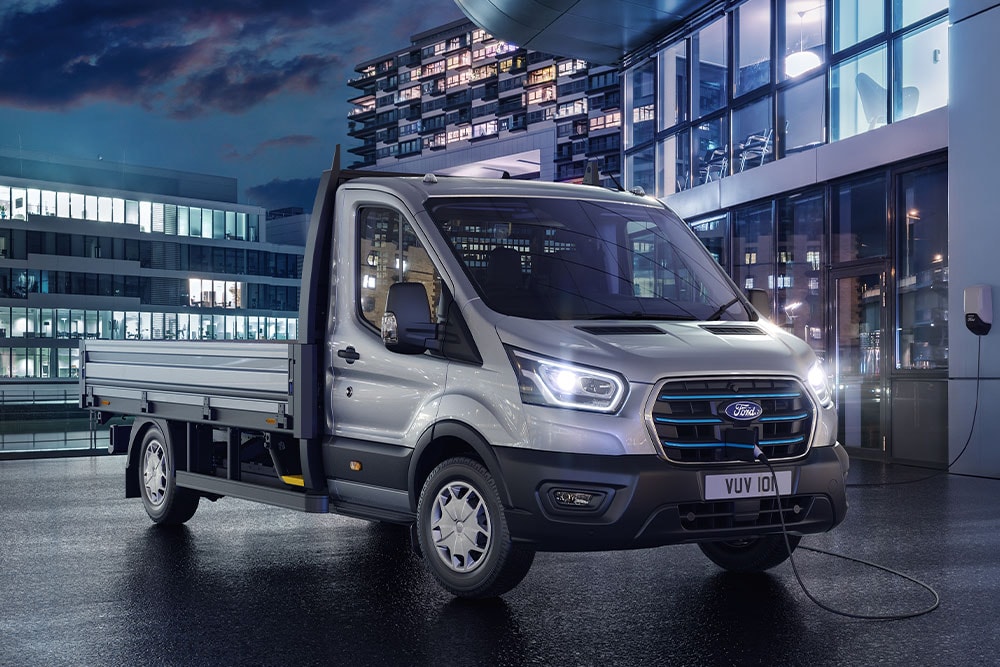 Hopeanvärinen Ford Transit Chassis Cab pysäköitynä modernin rakennuksen eteen iltamyöhään.