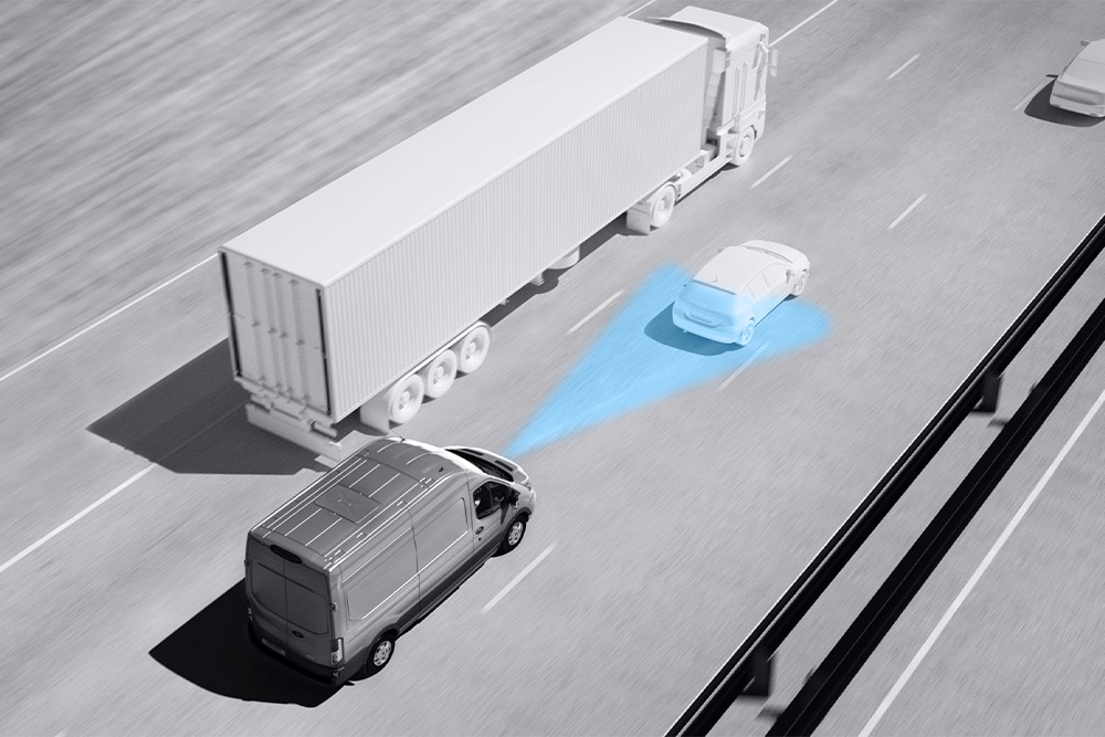 Harmaasävypiirros Ford Transit Vanista; siniset viivat tiellä kuvaavat kuljettajaa avustavien edistyksellisten järjestelmien käyttöä.