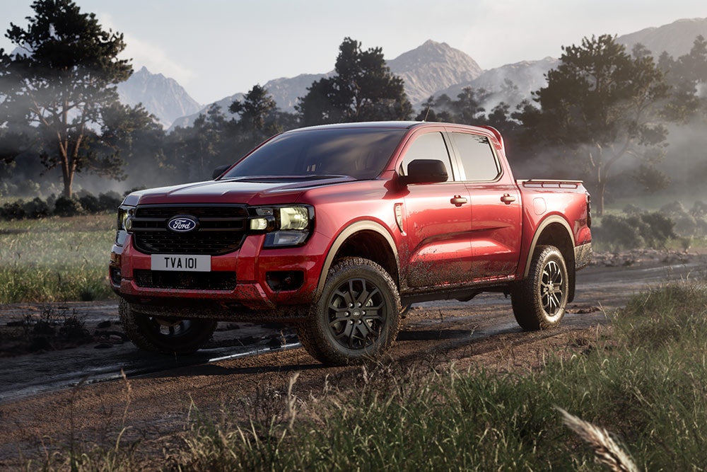 Punainen Ford Ranger Raptor ajaa hiekkatietä pitkin kauniissa maisemassa.