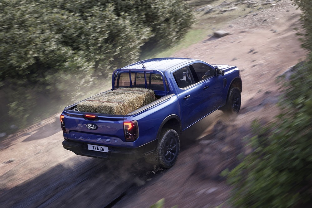 Yltäältä takaapäin kuvattu sininen Ford Ranger ajaa hiekkatietä pitkin.