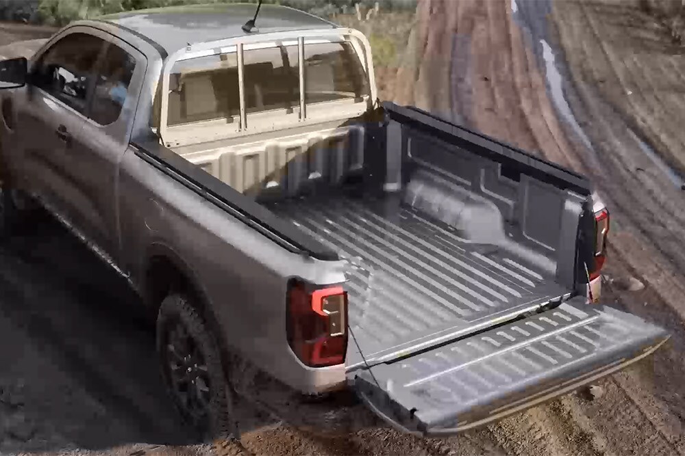 Takaa yläviistosta kuvattu hopeanvärinen Ford Ranger XLT Super Cab pysäköitynä mutaiselle tielle takalaita auki.