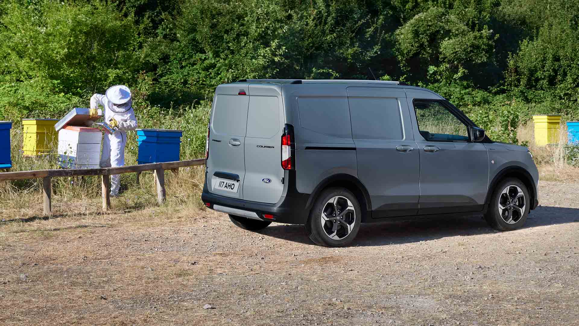 Mehiläishoitaja työskentelemässä Ford Transit Courierin vieressä