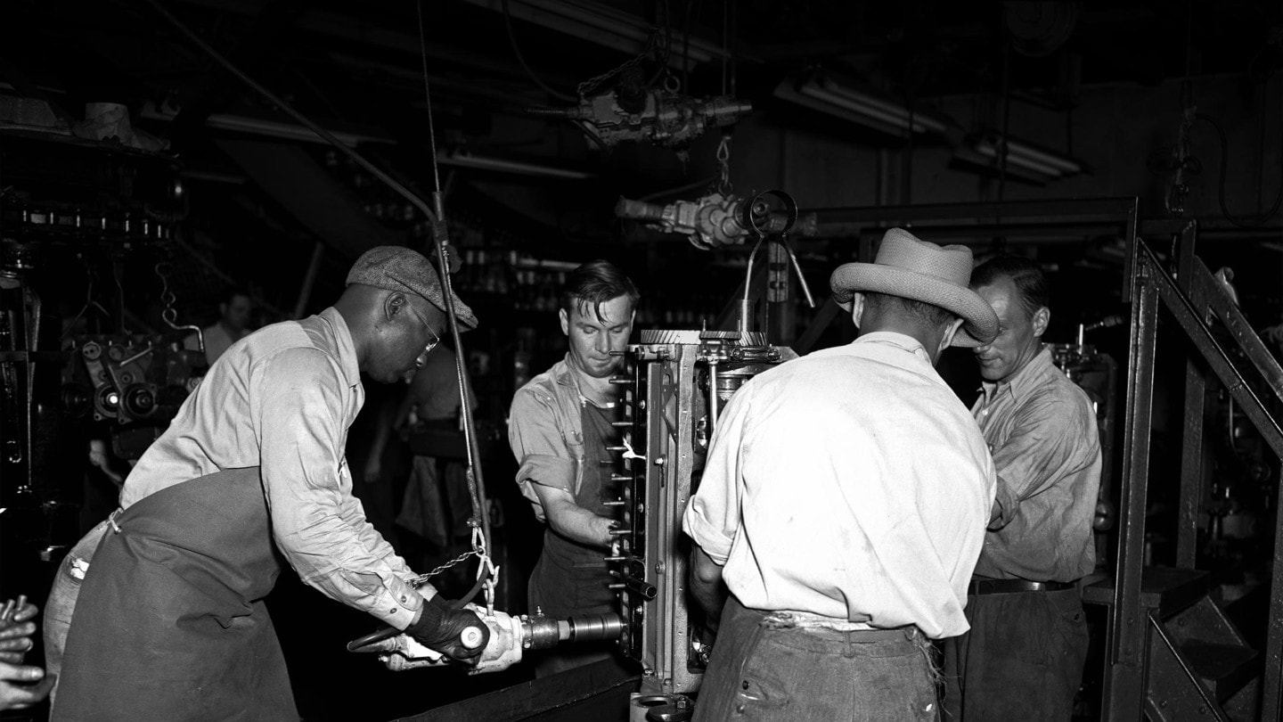 Ryhmä ihmisiä työskentelemässä kokoonpanolinjalla tehtaassa.