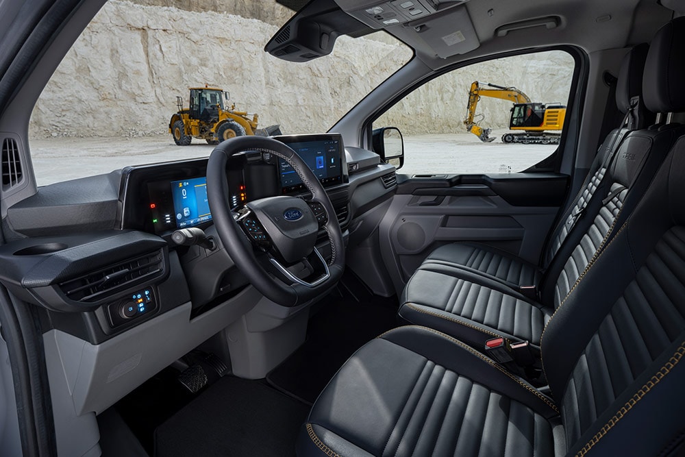 Sisältä kuvattu näkymä Ford Transit Custom -pakettiautosta; näkyvissä kojelauta, ohjauspyörä ja istuimet.