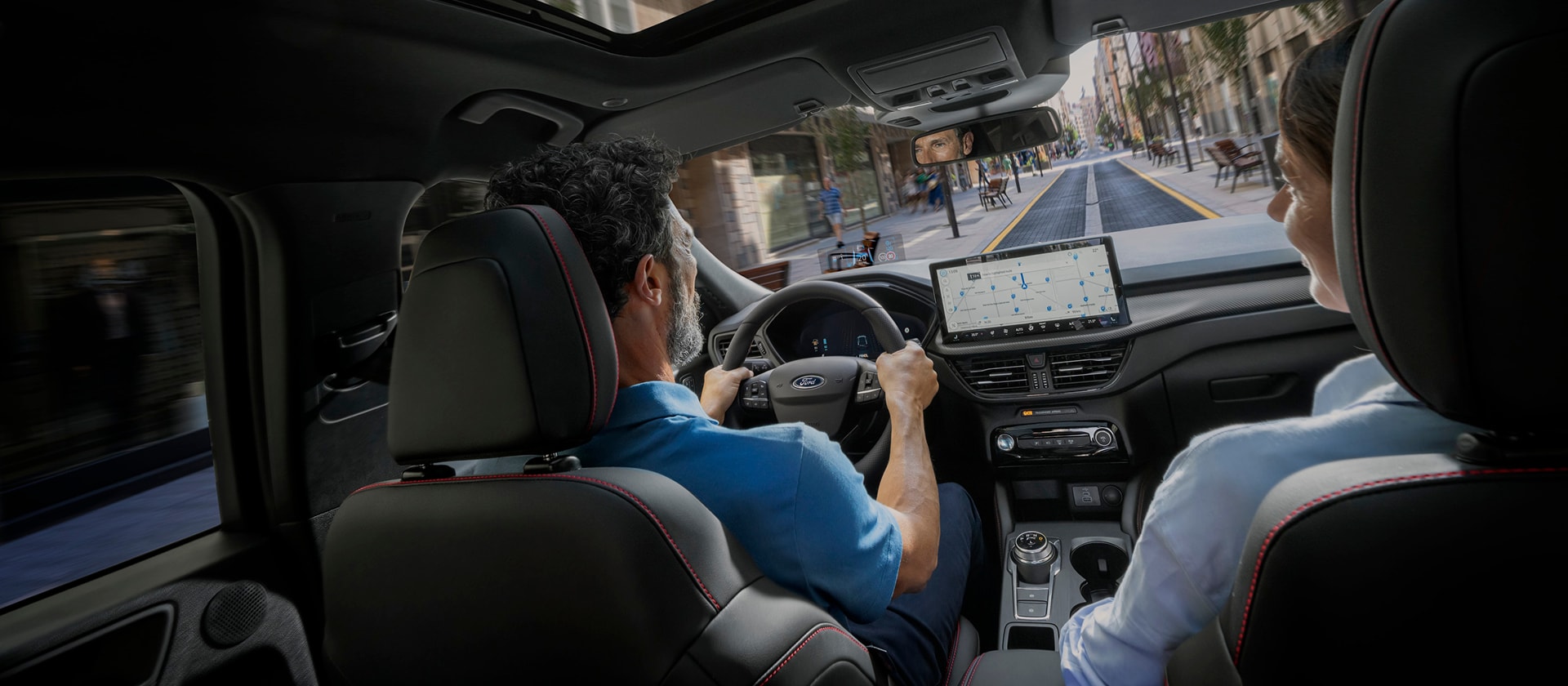 Matkustajat Ford-ajoneuvossa, jonka SYNC-digitaalinäyttö auttaa navigoimaan kaupunkireitillä.