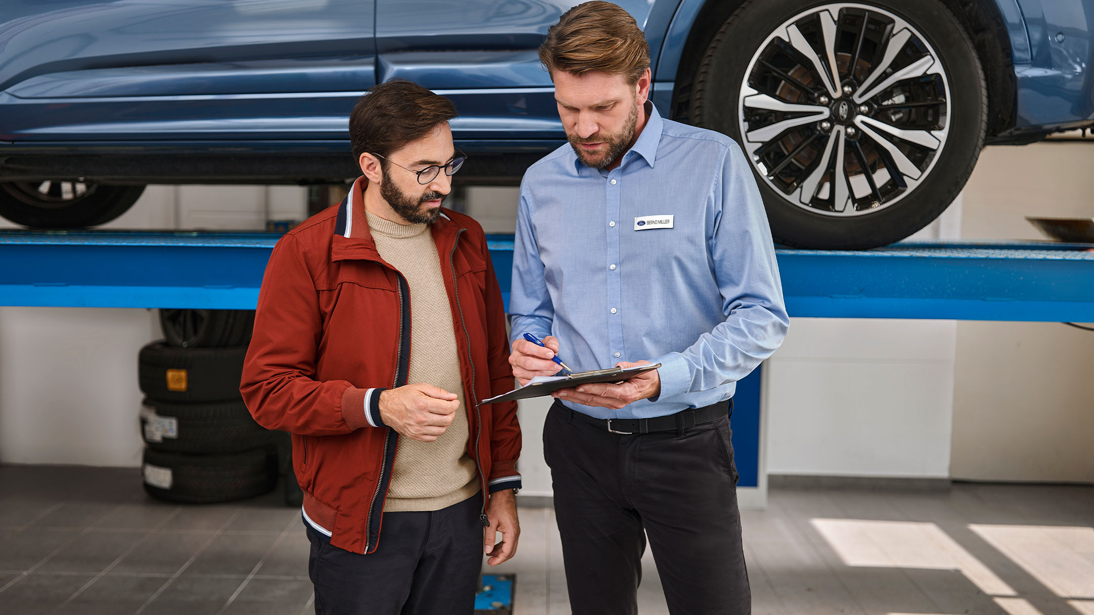 Henkilö puhuu Ford-asiantuntijan kanssa Ford-huoltokeskuksessa. 
