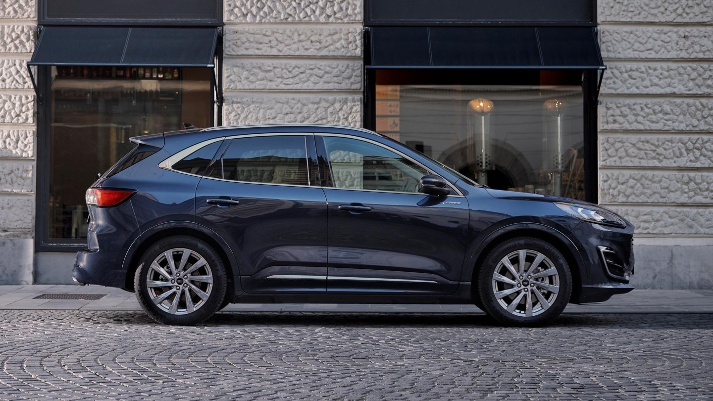 Ford Kuga -katumaasturi parkissa kaupunkiympäristössä, kuvattuna sivusta.
